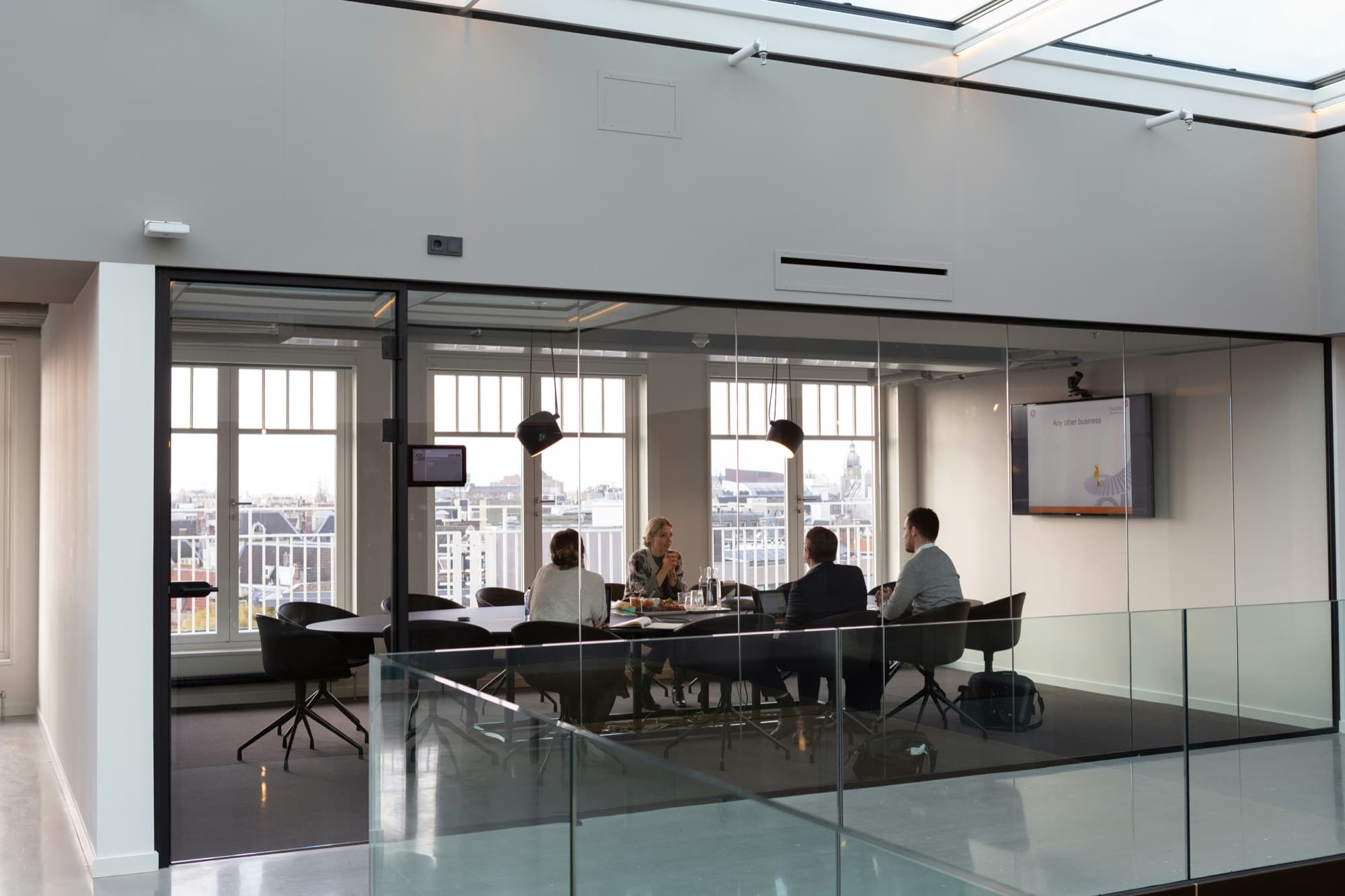 Client meeting in progress in a bright top-floor boardroom, viewed through a glass wall