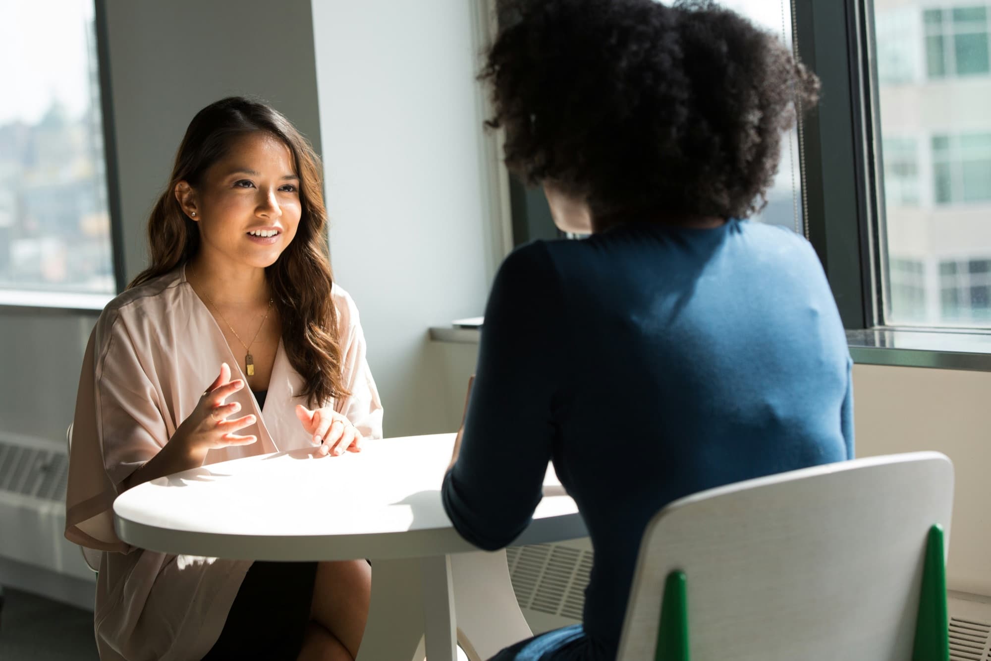 Two women in a bright office meeting across a small table